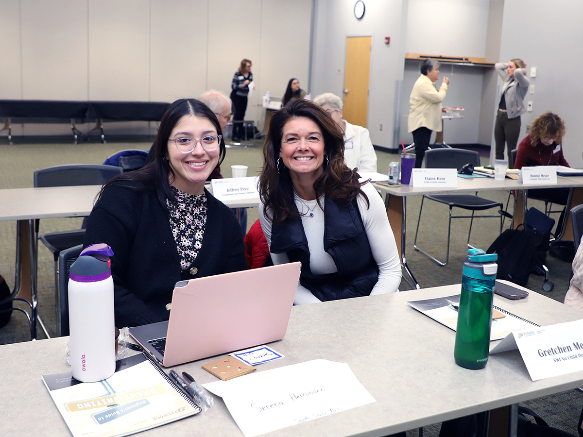 Two women sitting at a table smiling