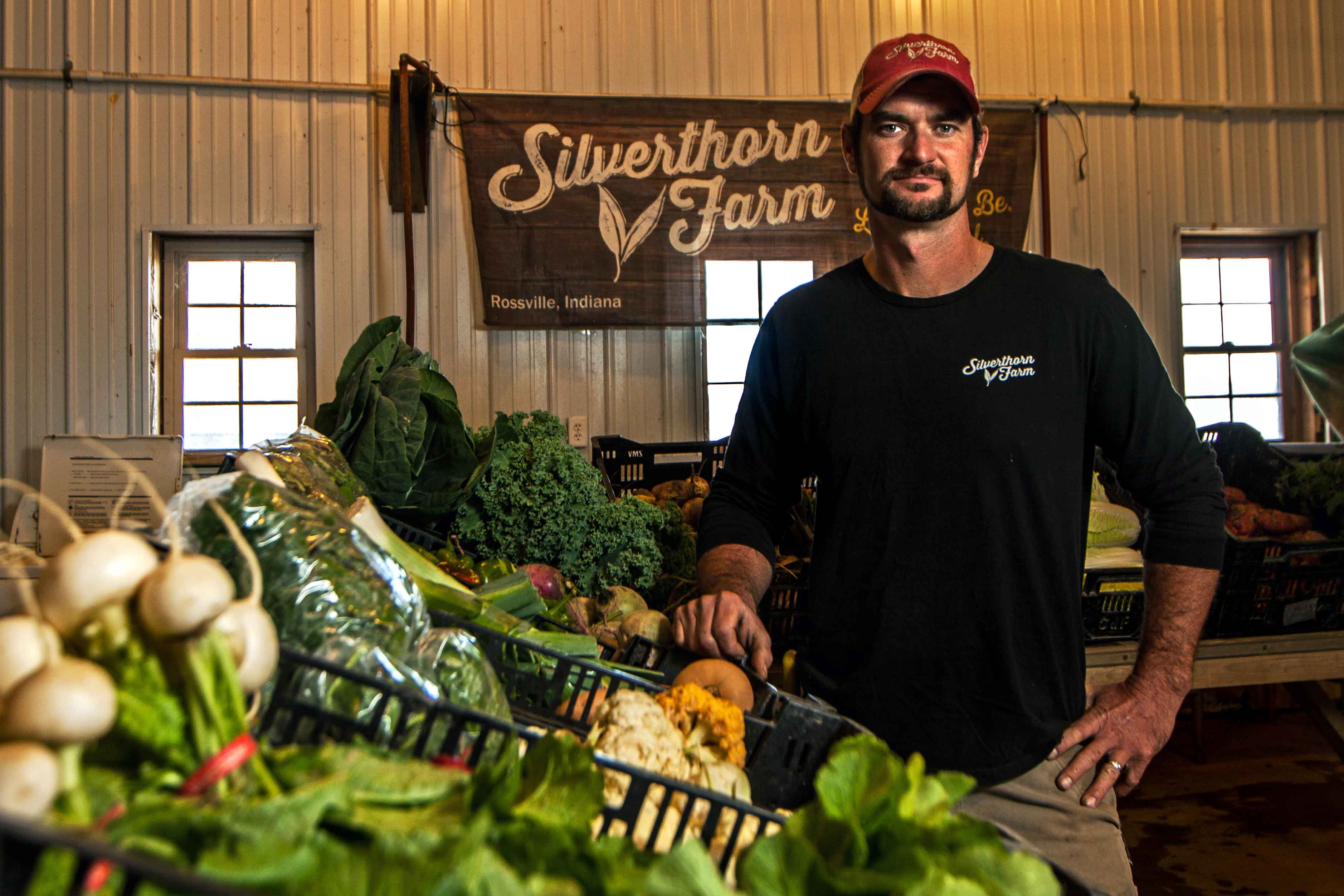 Image of a man standing next to a stand of produce.