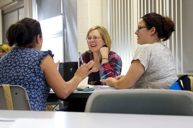 Image of three women sitting at a table and talking