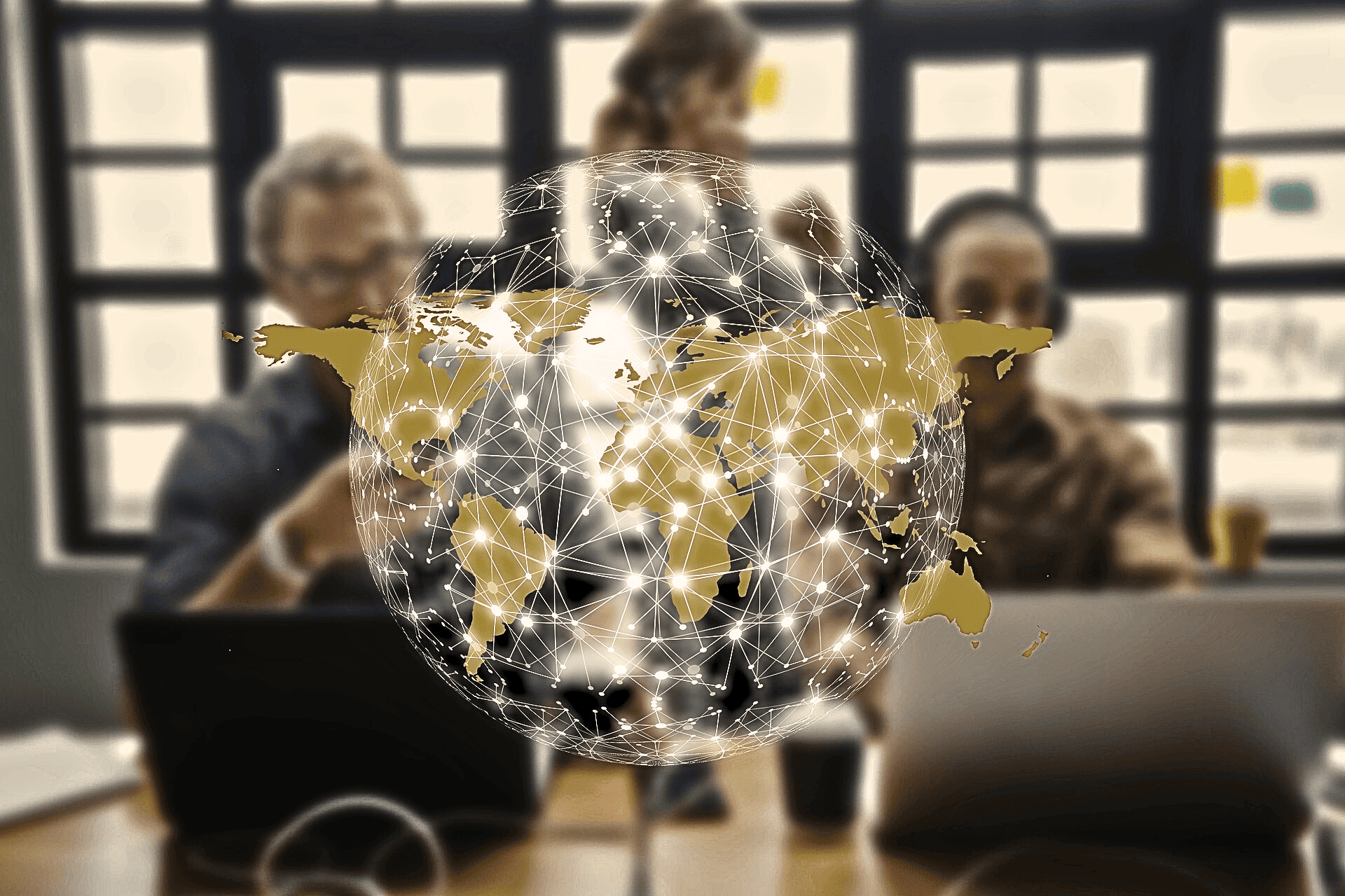 People working in an office behind a digital world map graphic.