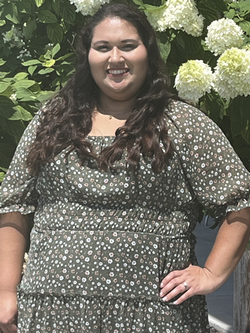 Image of our Communications & Marketing Administrative Assistant Hayley Kinley in front of a hydrangea flower tree