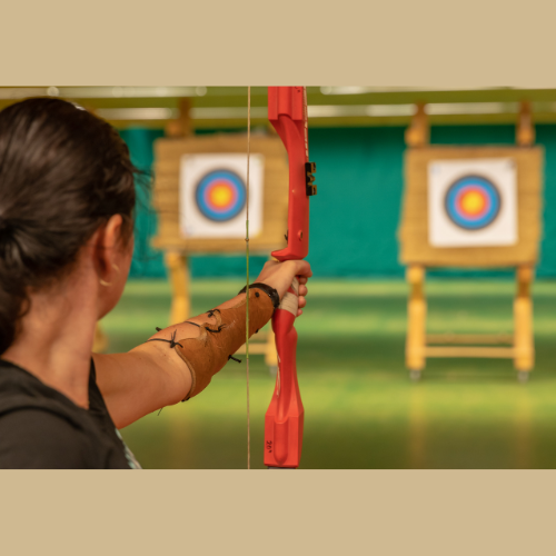 boy aiming bow and arrow at target board