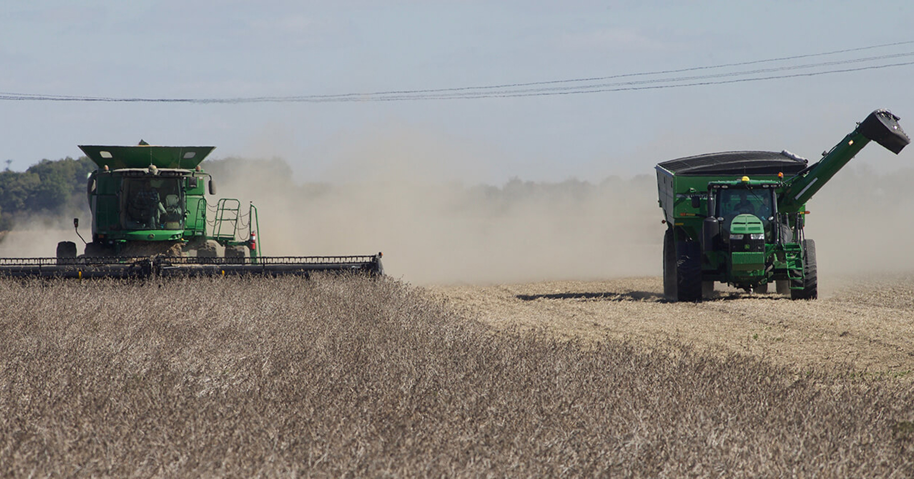 Two farm vehicles harvesting a field
