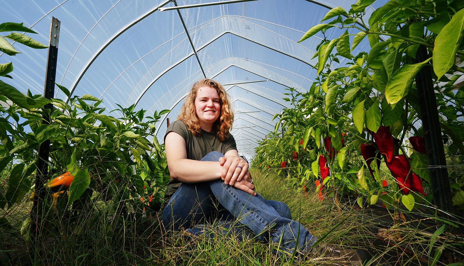 Ashley Adair sits in a greenhouse with organic peppers.