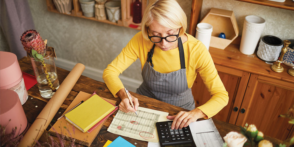Woman seated at desk is caculating her budget and managing her personal finances.