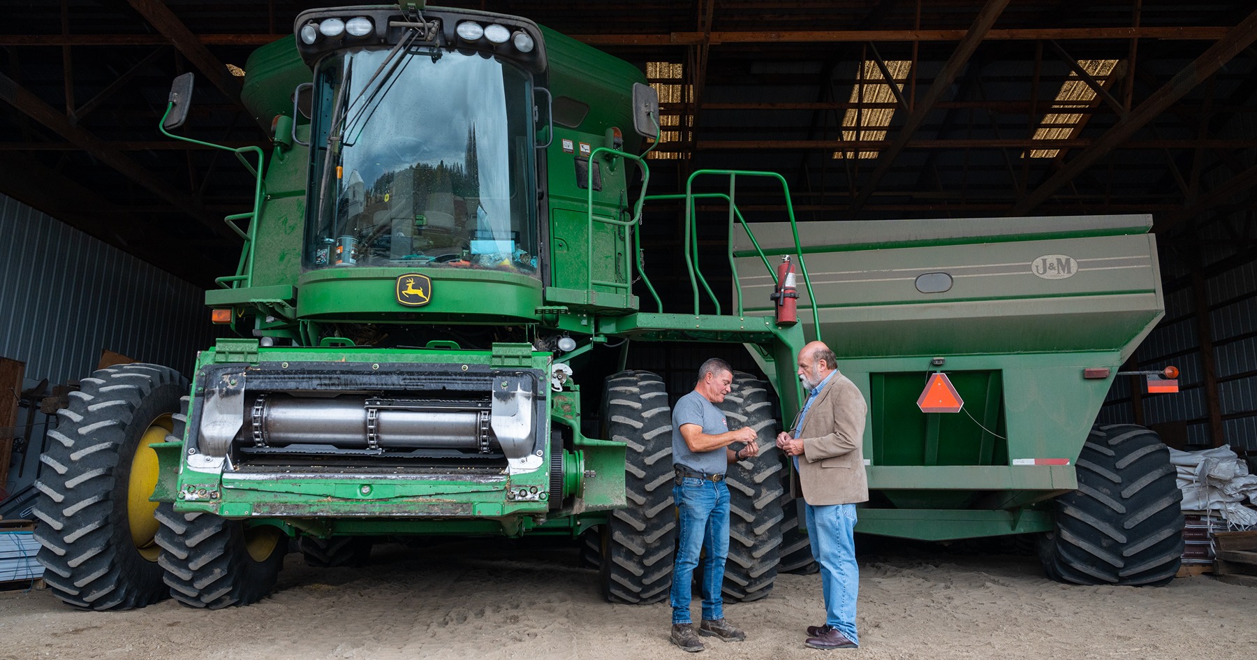 Fred Whitfrd talks to a man in front of a large farm vehicle.
