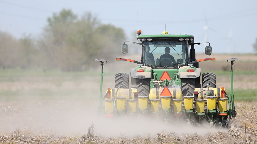  A farmer drives a no-till tractor over a field harvested the previous fall.