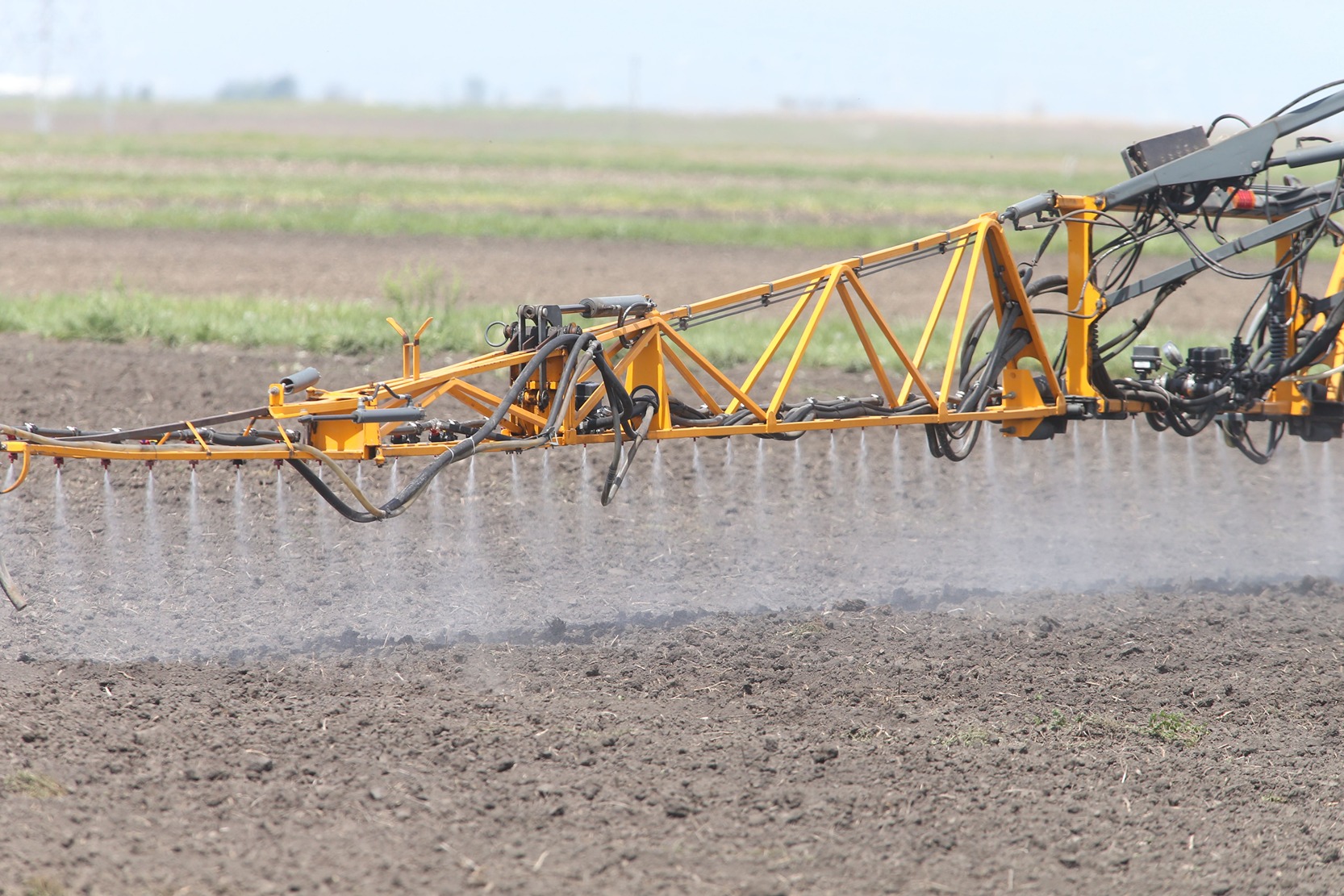 A crop sprayer is spraying pesticides on a field.