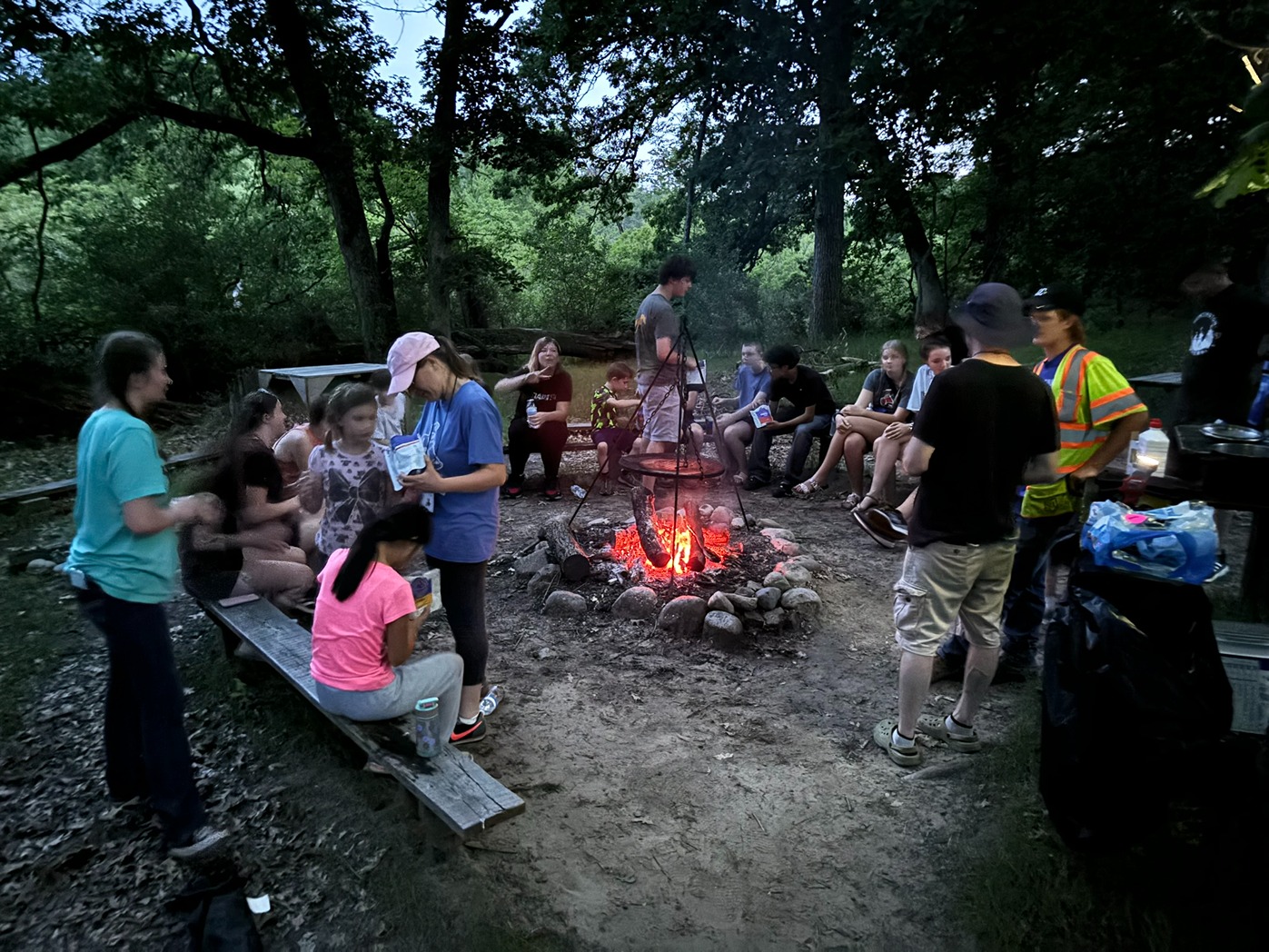 4-H camp councelors standing around a campfire in the woods
