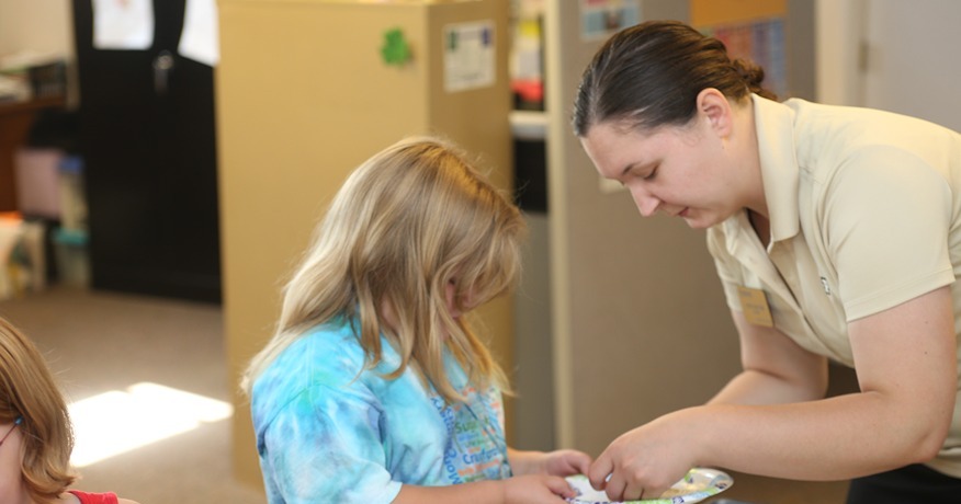 A woman puts food on a girl’s plate.