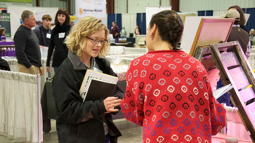 Two women, an attendee and a vendor, talk at the Small Farm Conference trade show.