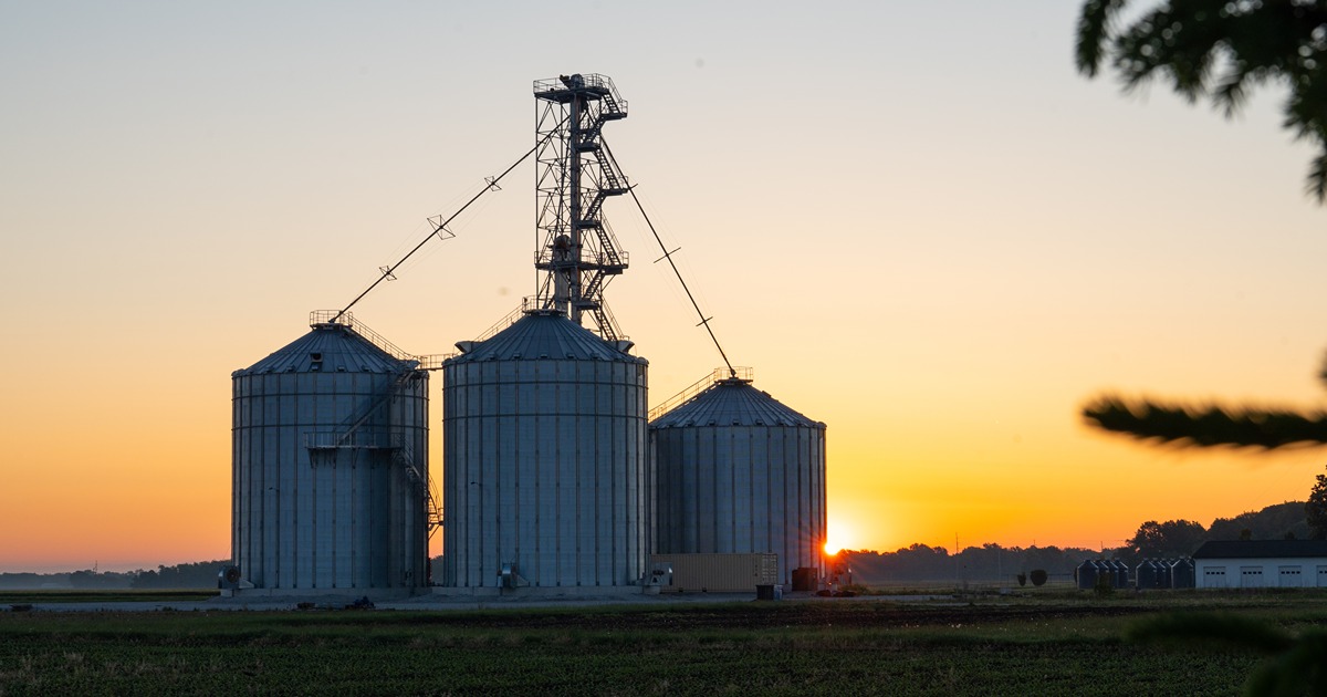 Three grain bins standing with the sun behind them.