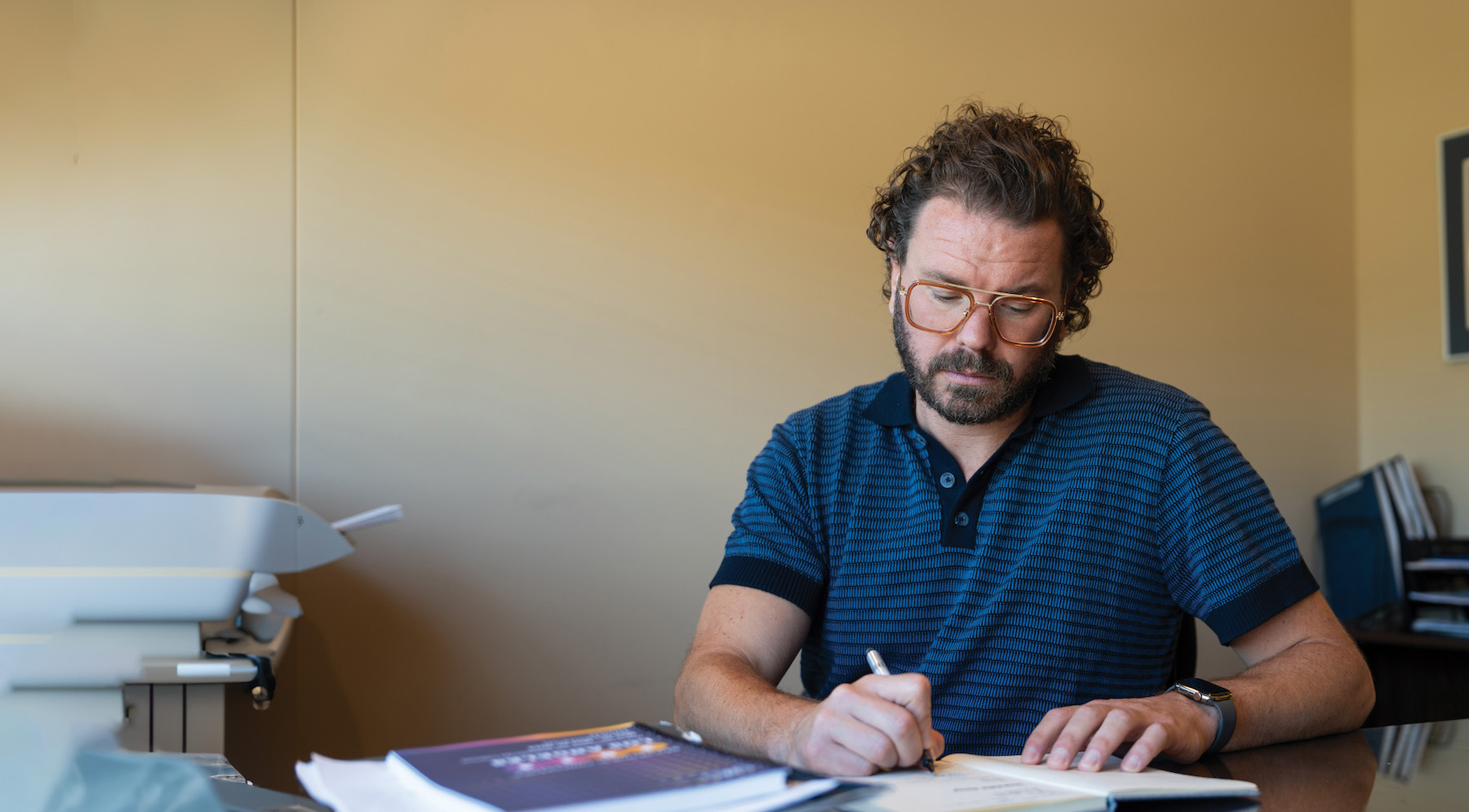 male adult writing notes at his desk
