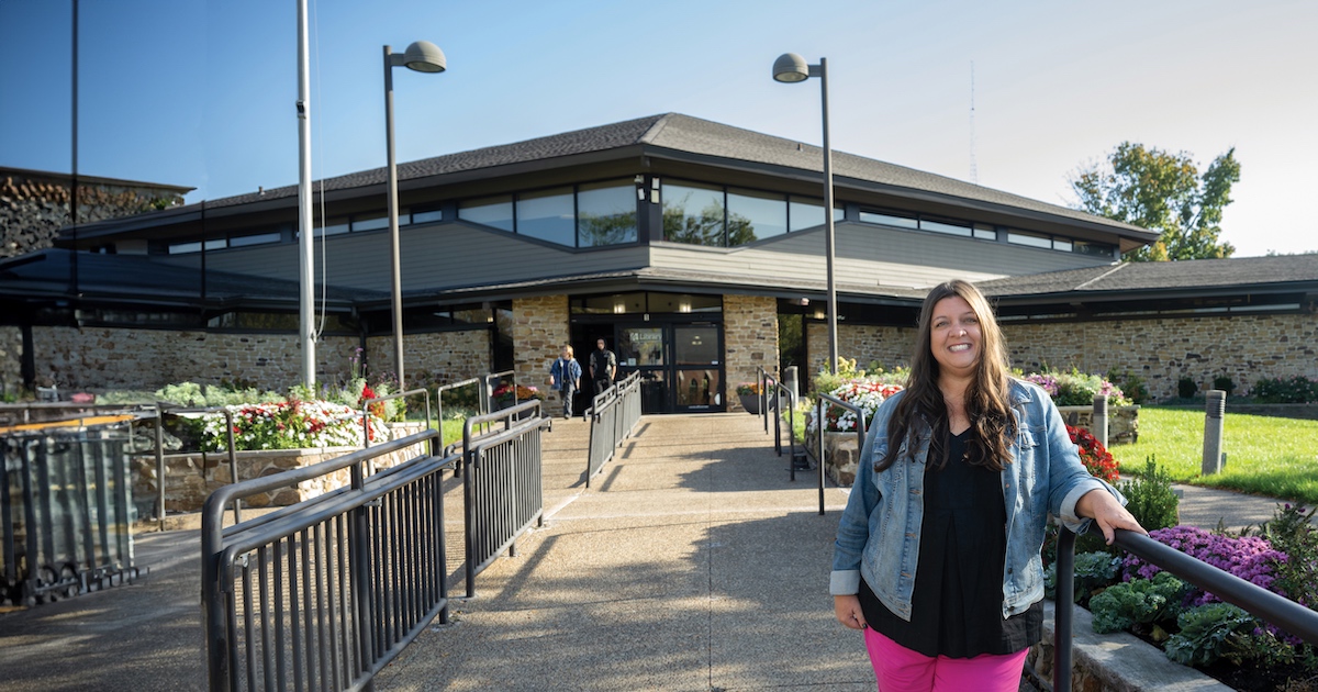 woman in front of a building smiling a the camera