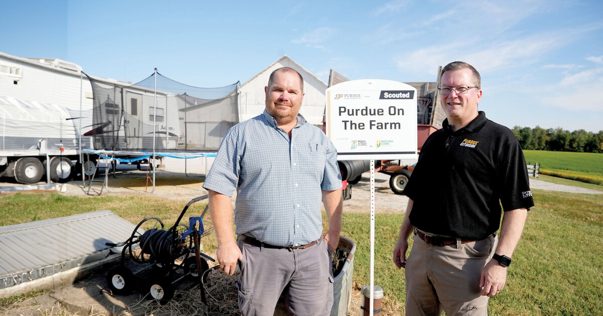 two male adults in front of fram equipment outdoors
