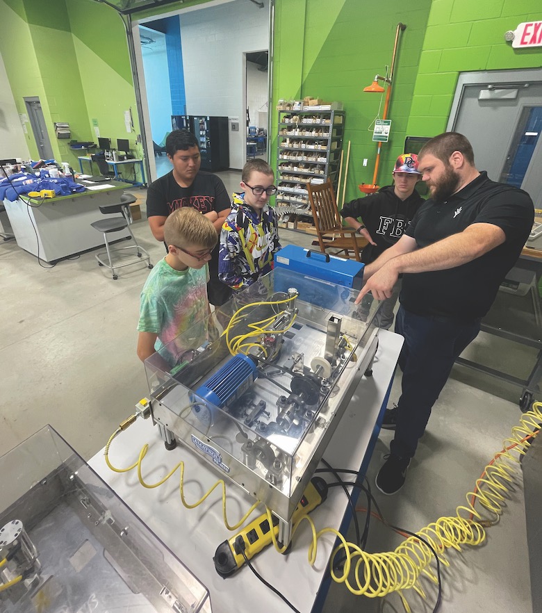 Instructor making a demonstration to kids with an industrial robot 