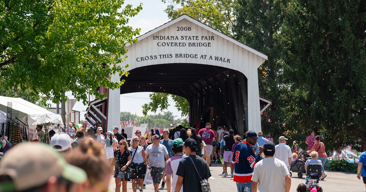 People walk under the Indiana State Fair covered bridge.