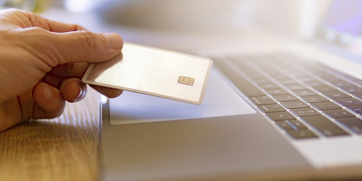 person holding credit card by laptop