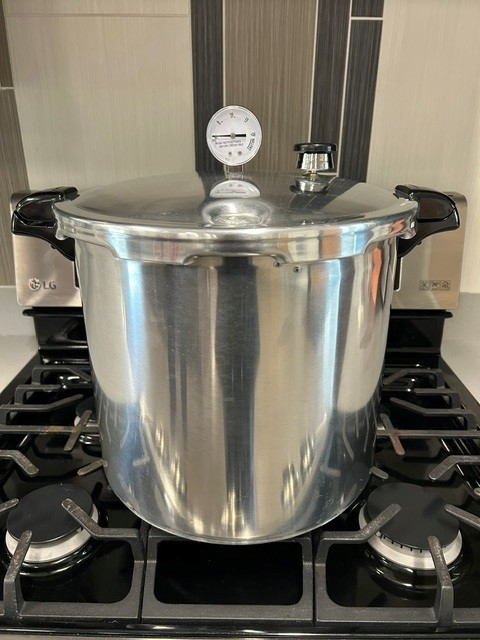 Pressure canner with lid and dial gauge on stove top