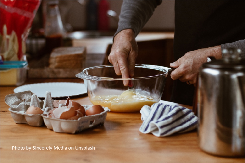 Image of a a man beating eggs on a bowl in a kitchen